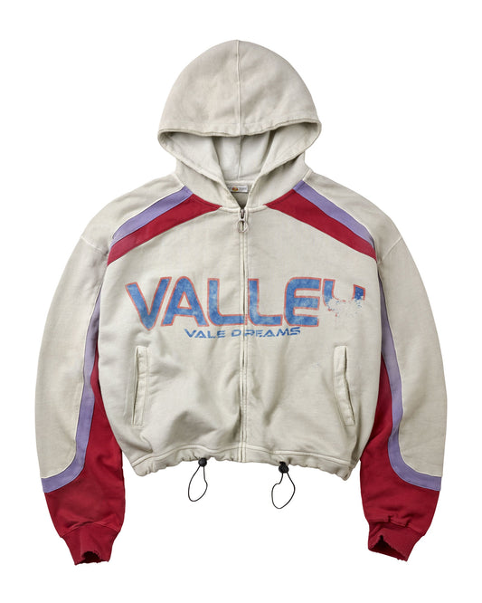 A cream-colored zip-up hoodie with red and purple color-blocked details on the shoulders and sleeves, featuring 'VALLEY' and 'VALE DREAMS' printed in blue across the chest.