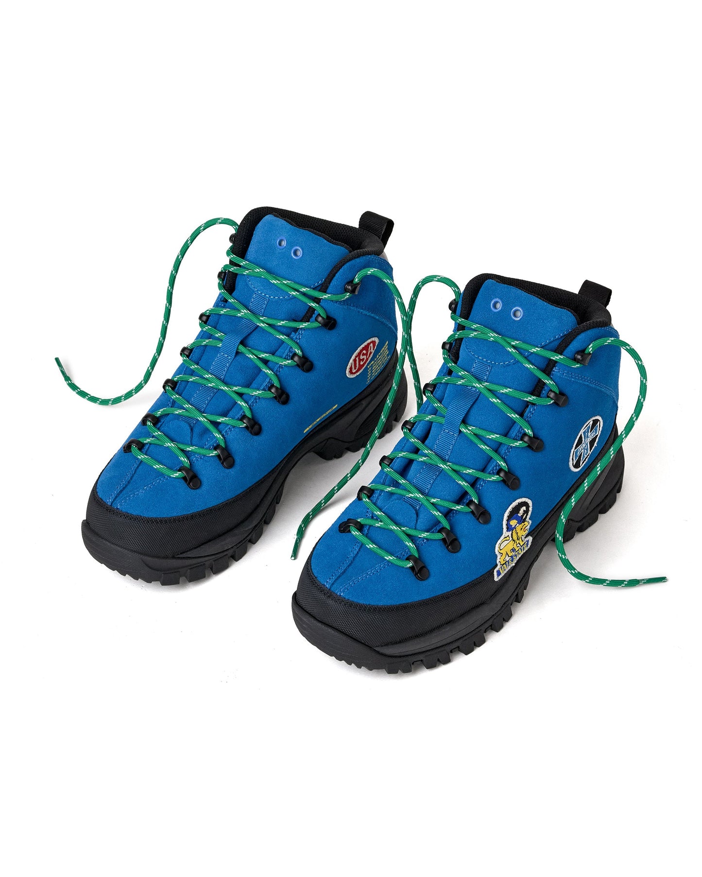 A pair of blue and black high-top hiking boots with green laces,. The boots feature various patches.