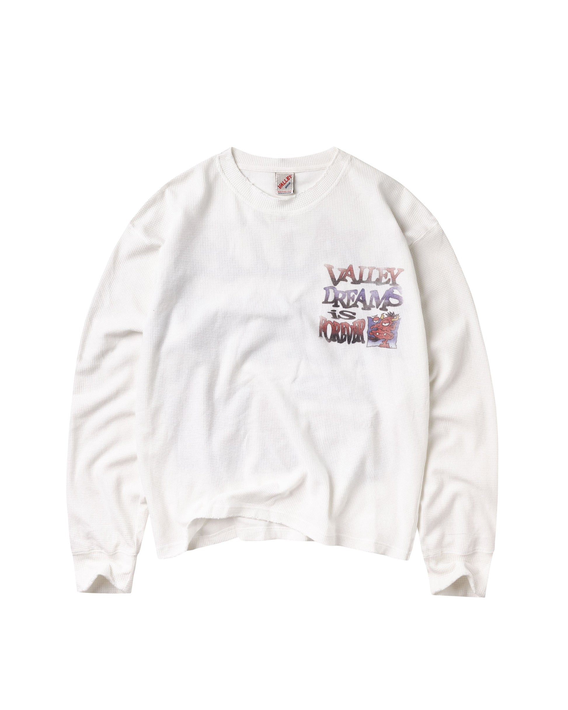 A white long-sleeve t-shirt with a colorful graphic on the left chest that reads 'VALLEY DREAMS IS FOREVER' in a graffiti-style font, displayed flat against a white background.