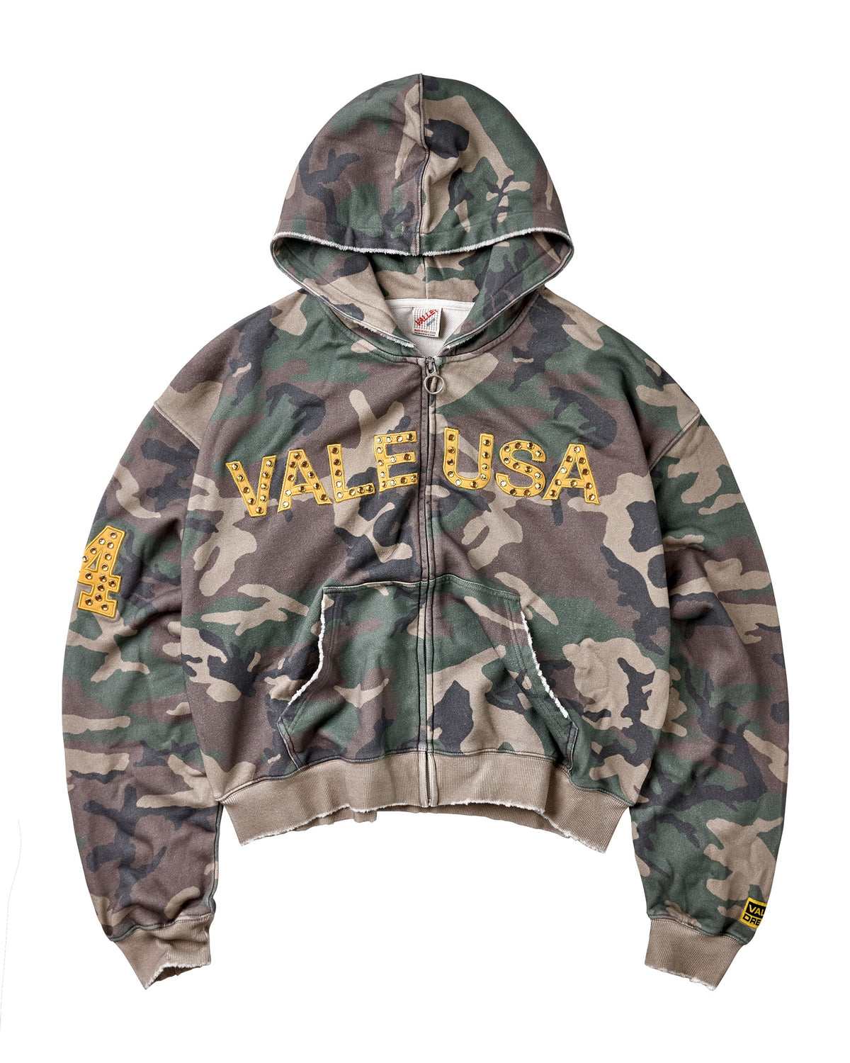 A camouflage zip-up hoodie with 'VALE USA' printed across the chest in yellow letters with small gold star details, featuring a distressed raw hem .