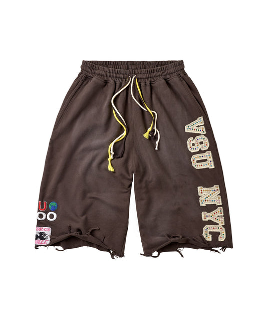 Dark brown athletic shorts with a distressed raw hem, featuring a yellow and white drawstring, 'VSU NYC' text printed vertically on the right leg, and a colorful patch on the left leg.